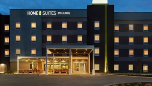 A hotel with a modern facade, multiple floors, and a well-lit entrance area with seating outside. - Home2 Suites by Hilton Lawrenceville Atlanta Sugarloaf, GA (Lawrenceville)