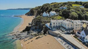 A coastal property with a beach, houses, and a cliff overlooking the sea.