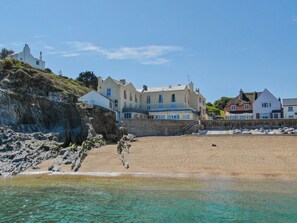 A coastal building with multiple stories, situated on a rocky cliff overlooking a sandy beach. - 14 At The Beach, Torcross -  an apartment that sleeps 4 guests  in 2 bedrooms (Torcross)