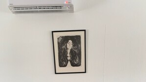 A wooden dining table with six chairs, an air conditioning unit above it, and a framed artwork on the wall. - Four Bedroom Guesthouse in Fjerdingen, Harran (Fjerdingen)