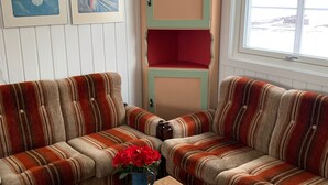 A living room with striped sofas, a wooden coffee table, and a vase with red flowers. - Four Bedroom Guesthouse in Fjerdingen, Harran (Fjerdingen)