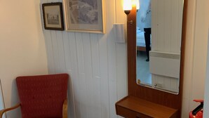 A room with a wooden vanity, a red chair, a framed picture on the wall, and a bedside lamp. - Four Bedroom Guesthouse in Fjerdingen, Harran (Fjerdingen)