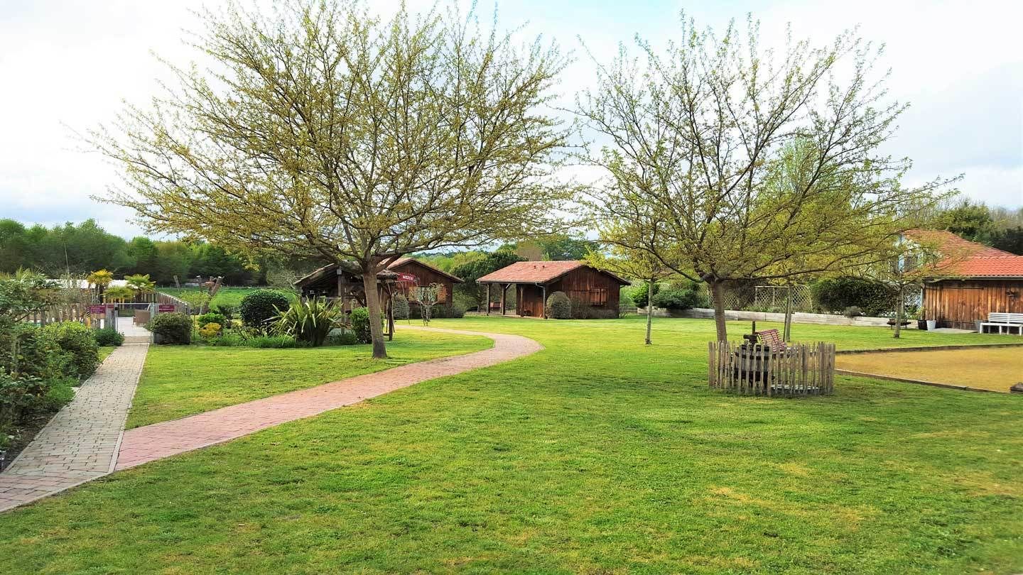 A grassy area with a paved path leading to a wooden structure.