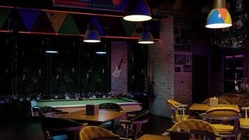 A bar area with pool tables, leather chairs, and hanging lamps.