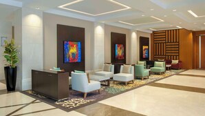 A modern lobby with a reception desk, seating area, and artwork on the walls. - DoubleTree by Hilton Doha - Al Sadd (Doha)