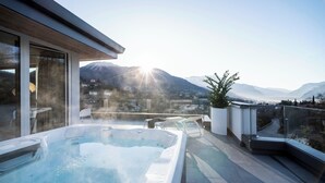 A rooftop terrace with a hot tub, glass railings, and a mountain view. - Be Place (Trento)