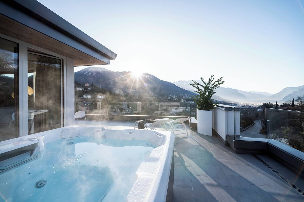 Une terrasse sur le toit dotée d’un jacuzzi, de rampes en verre et offrant une vue sur les montagnes.