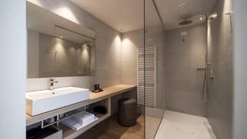 A modern bathroom with a glass-enclosed shower, a white sink, and a wooden vanity.