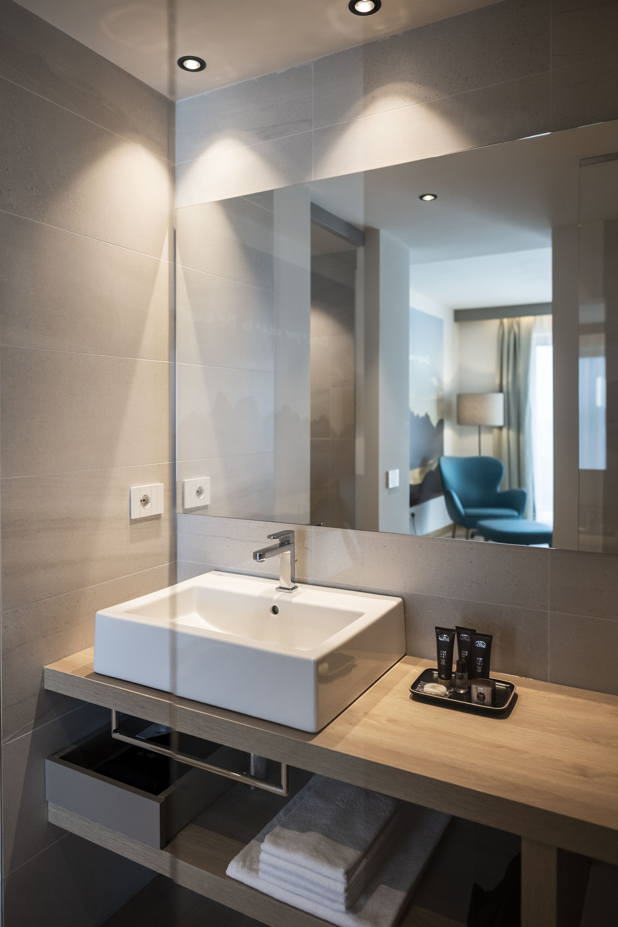 Un baño moderno con un espejo grande, un lavabo blanco y un perchero para toallas.