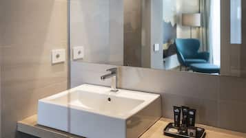 Un baño moderno con un espejo grande, un lavabo blanco y un perchero para toallas.