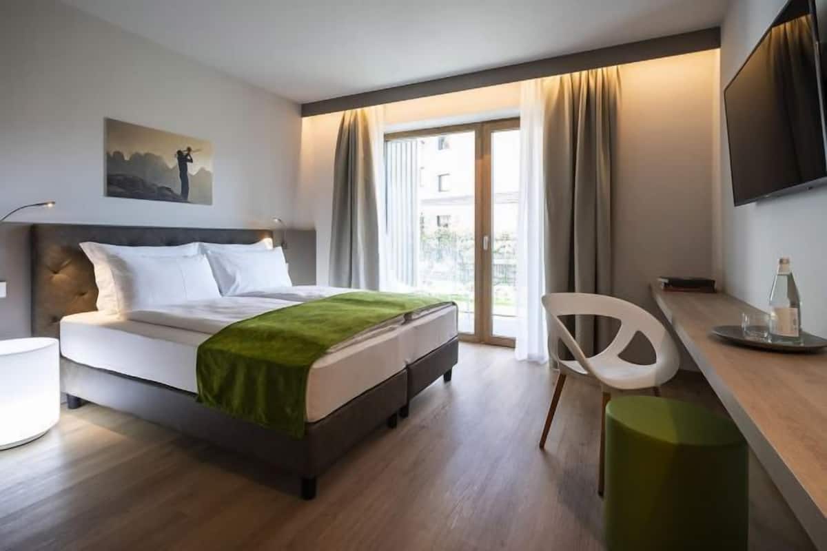 Une chambre d’hôtel moderne équipée d’un lit, d’un bureau, d’une chaise et d’un téléviseur.