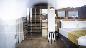 A modern hotel room with a bed, a small table, and a view of a mountain. - Be Place (Trento)
