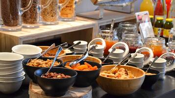 A buffet with various food items and containers, including bowls of cereal, fruits, and condiments.