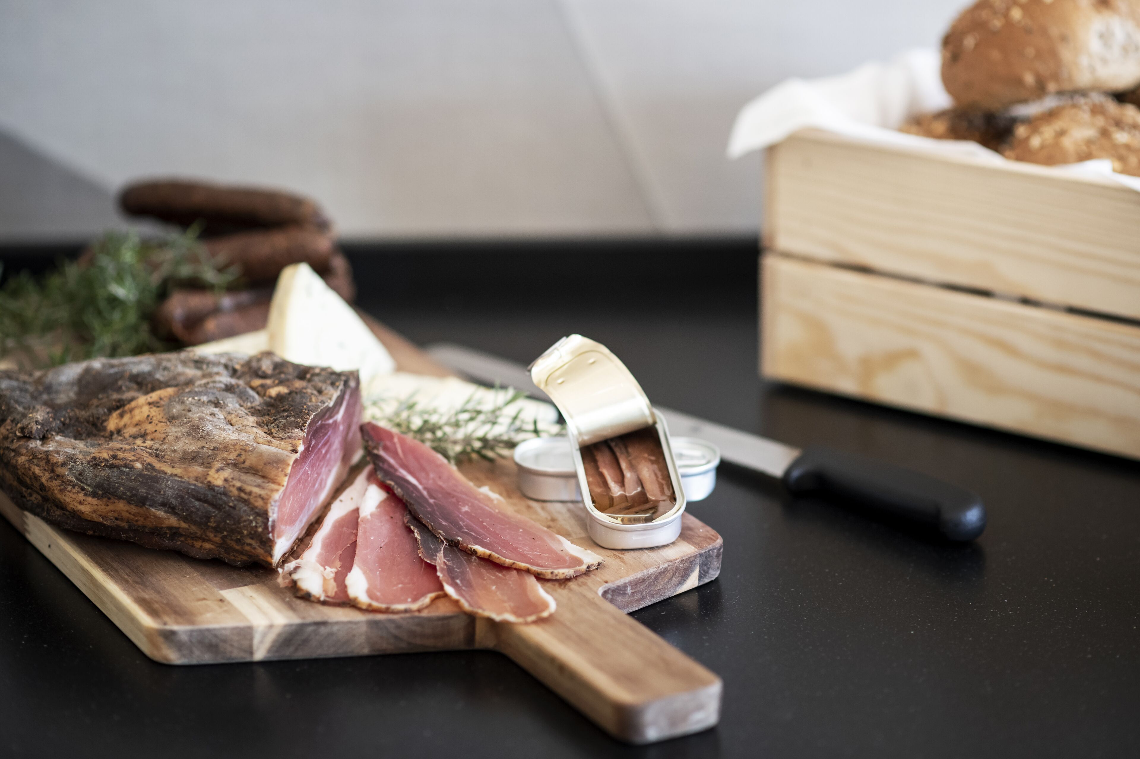 A charcuterie board with various meats, cheese, and bread on a wooden cutting board.