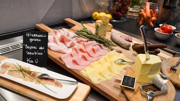Eine Platte mit verschiedenen Wurstwaren, Käsesorten und Kräutern.