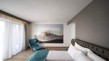 Una camera d'albergo moderna con un letto grande, una poltrona blu, una lampada da terra e un murale panoramico.