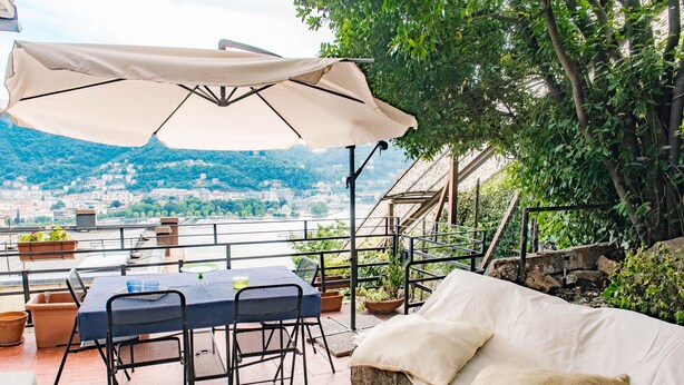 Une terrasse extérieure avec une table et des chaises, un canapé et un grand parasol.