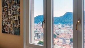 Une vue à travers une fenêtre donnant sur un paysage urbain, avec des bâtiments et une colline.