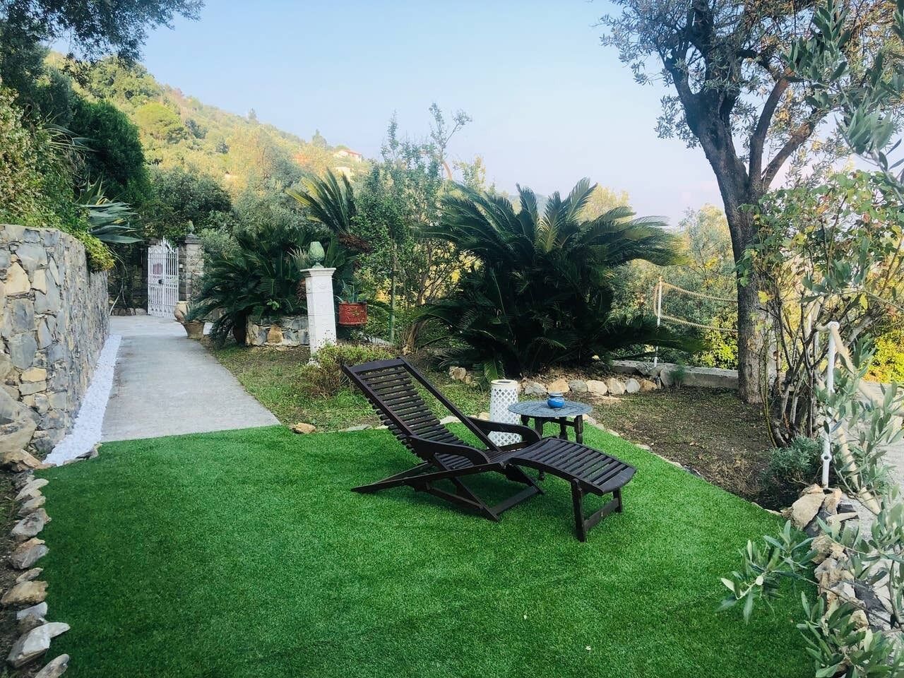 A garden with a paved path, two lounge chairs, and a small table.