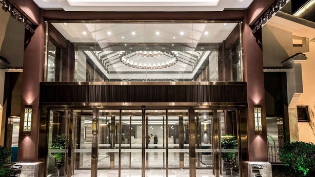 Ein Hotel Eingang mit Glastür, einer zentralen Chandelier und einem Marmorboden.