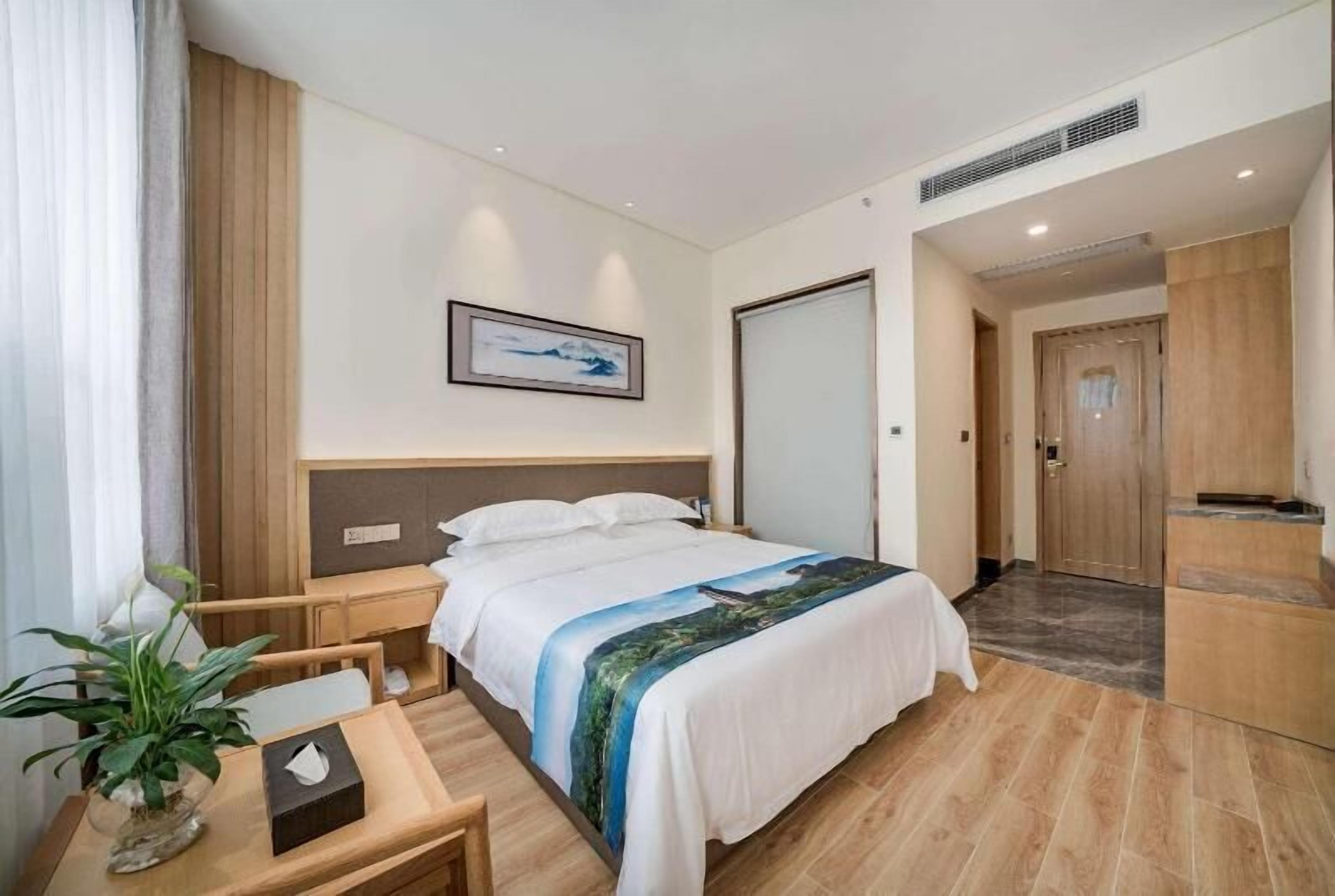 Ein Hotelzimmer mit Bett, Nachttisch, Lampe und einem Bild an der Wand.