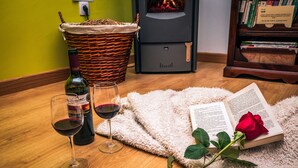 A cozy reading area with a wicker basket, a wine bottle, two wine glasses, a fluffy rug, a book, and a rose. - Casa Rural Aguas Frías I, II y III for 2 people (Riello)