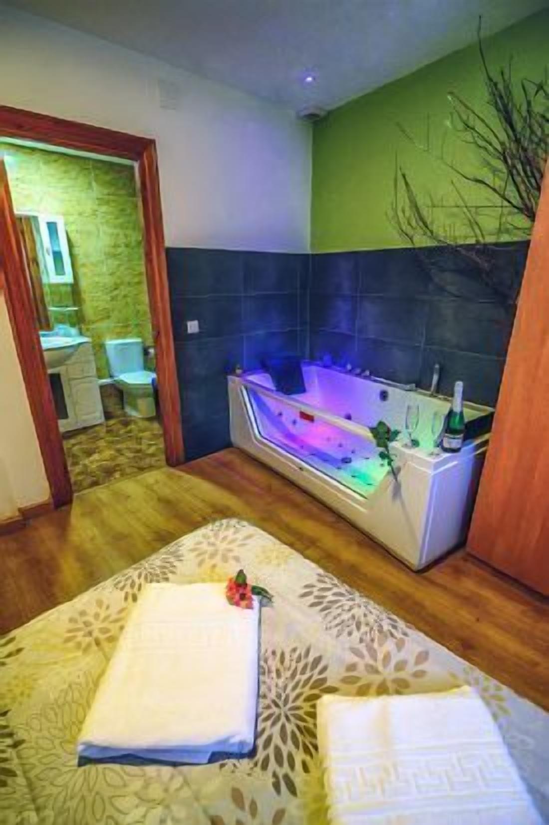 Une salle de bain avec une baignoire, un miroir et un mur vert.