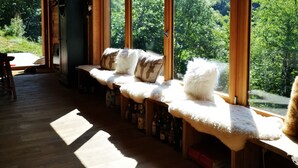 Un intérieur en bois avec de grandes fenêtres donnant sur une région montagneuse couverte de forêts.