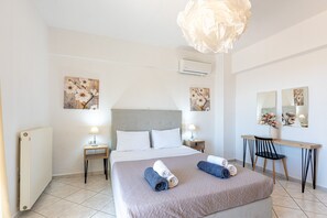 A hotel room with a bed, bedside tables, a desk, a chair, and artwork on the walls. - Charmful villa, stunning views,pool, hot tub & BBQ (Roussospiti)