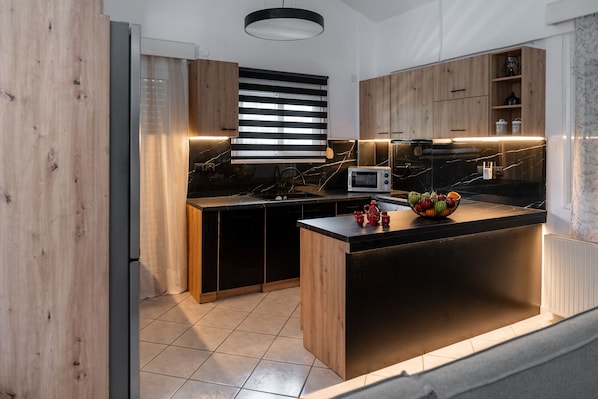 Une cuisine moderne avec des meubles en bois, un plan de travail noir et un four à micro-ondes encastré.