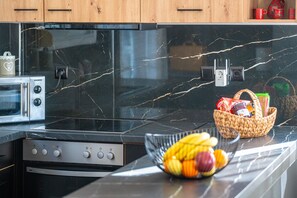 Une cuisine dotée d’un plan de travail en marbre noir, d’un four encastré, d’un four à micro-ondes et d’un panier à fruits.