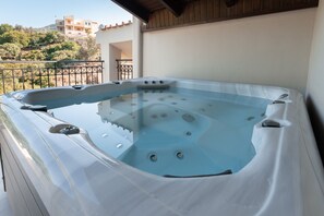 Un jacuzzi sur un balcon avec vue sur les bâtiments et les arbres.