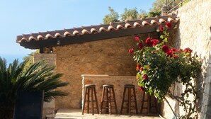 A stone building with a tiled roof, a pool, and a bar area with stools. - Charmful villa, stunning views,pool, hot tub & BBQ (Roussospiti)