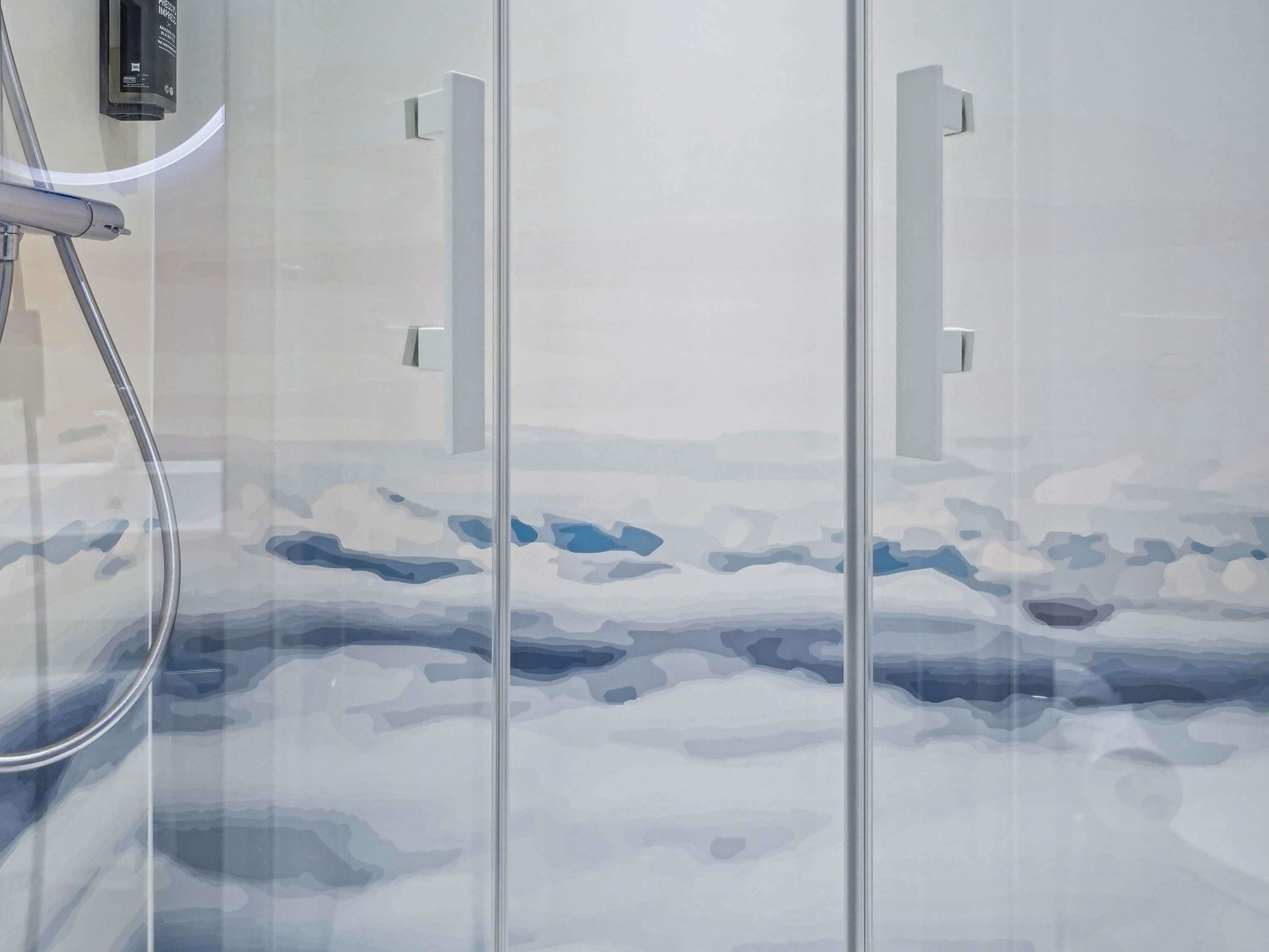 Une salle de bain dotée d’une douche à parois de verre, d’un pommeau de douche à main et d’un robinet mural.