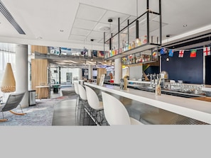 Un'area bar moderna con un lungo bancone, sgabelli da bar e una selezione di bottiglie.