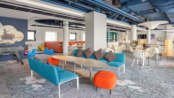 A modern lounge area with seating arrangements, a central table, and a mural on the wall.