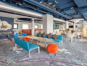 A modern lounge area with seating arrangements, a central table, and a mural on the wall. - ibis Styles Paris Orly Airport (Paray-Vieille-Poste)