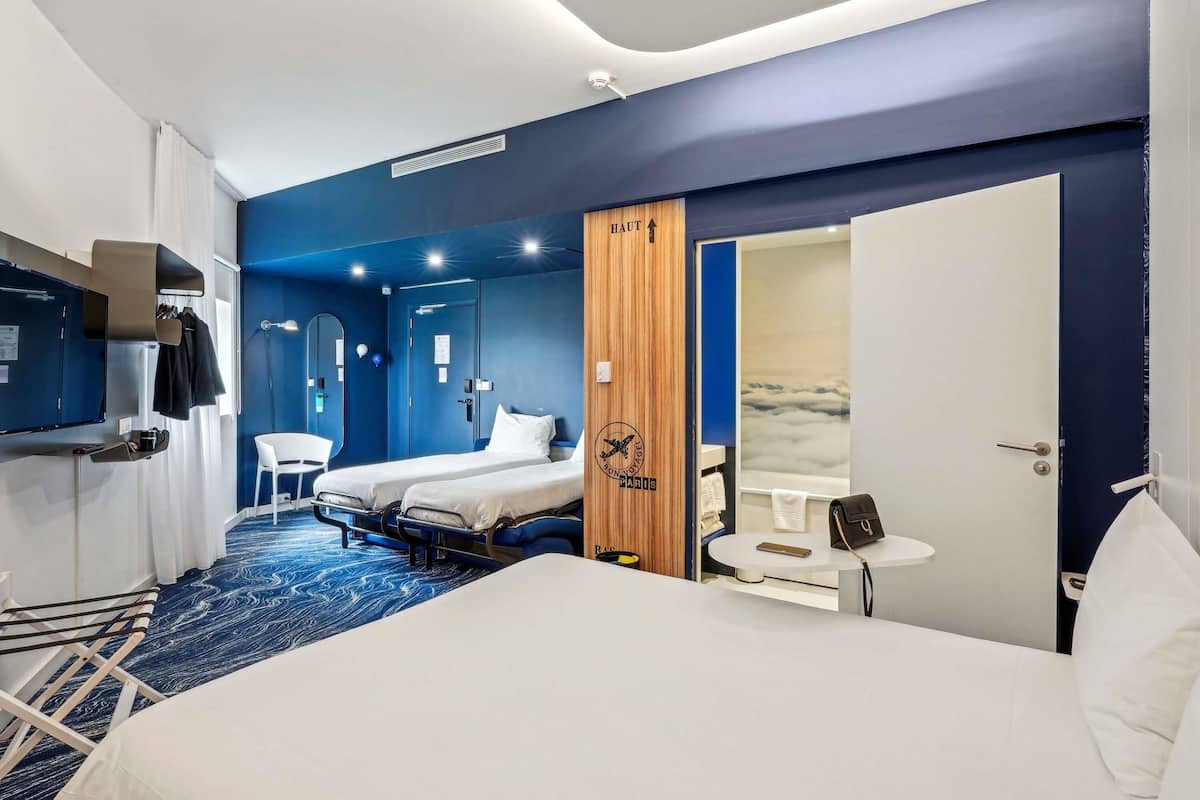 Una habitación de hotel con una cama, un escritorio, una silla, un televisor y un armario.