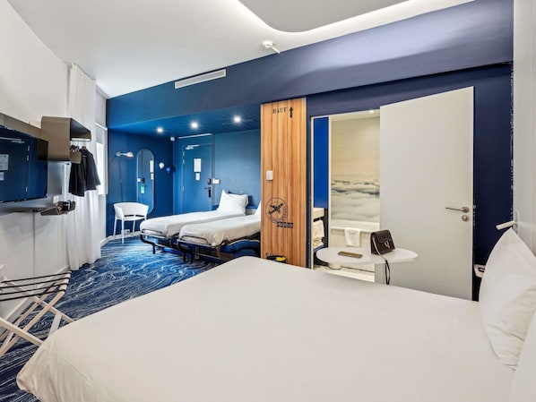 Ein Hotelzimmer mit Bett, Schreibtisch, Stuhl, Fernseher und Kleiderschrank.