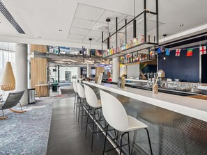 A modern bar area with a long counter, white bar stools, and a variety of bottles on shelves. - ibis Styles Paris Orly Airport (Paray-Vieille-Poste)