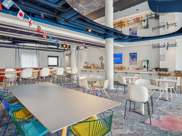 A modern conference room with white chairs, a large table, and a TV screen. Flags are hanging from the ceiling, and there are various items on the walls. - ibis Styles Paris Orly Airport (Paray-Vieille-Poste)