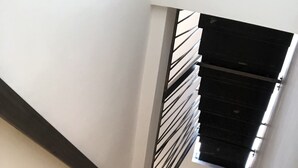 A modern staircase with a metal railing and a light fixture at the top. - The Mori's House, a house in the center close to the sea (Catania)