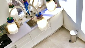 A modern kitchen with white cabinets, a built-in oven, and a dining area set for four with white chairs and a table set with plates, glasses, and cutlery. - The Mori's House, a house in the center close to the sea (Catania)