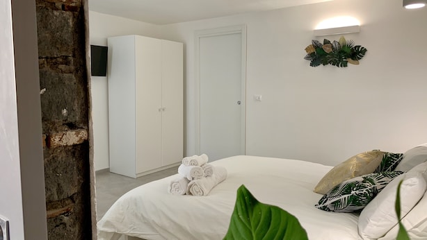 A bedroom with a bed, pillows, and a wall-mounted light fixture. - The Mori's House, a house in the center close to the sea (Catania)