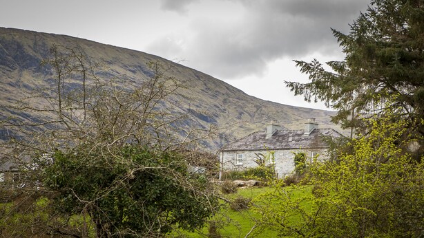 A stone house with a sloped roof, surrounded by greenery and a mountainous backdrop. - Carrowcullen, The Old Irish Farmhouse (Skreen, Ireland)