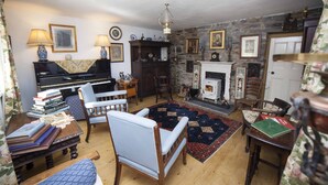 A traditional living room with a piano, a fireplace, and a stone wall. - Carrowcullen, The Old Irish Farmhouse (Skreen, Ireland)