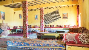 Una habitación tradicional con alfombras estampadas, muebles de madera y techo de paja.