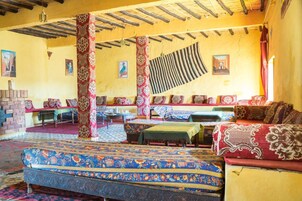 Una habitación tradicional con alfombras estampadas, muebles de madera y techo de paja.