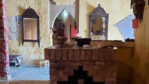 Una habitación tradicional con chimenea de ladrillo, techo de madera y alfombra estampada.
