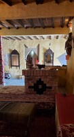 Una habitación tradicional con chimenea de ladrillo, techo de madera y alfombra estampada.